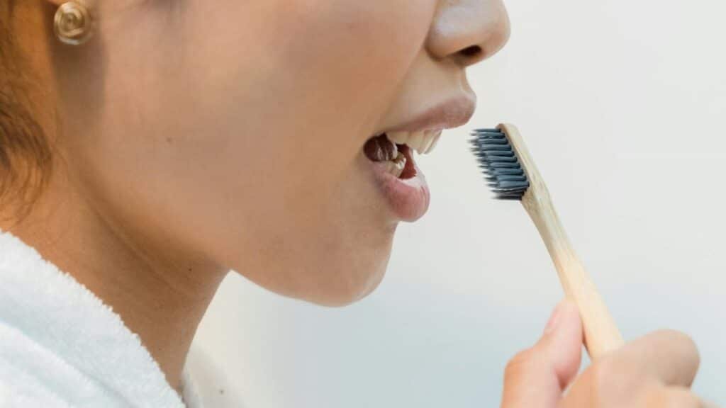 Close-up of a woman practicing oral hygiene with an eco-friendly bamboo toothbrush.