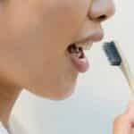 Close-up of a woman practicing oral hygiene with an eco-friendly bamboo toothbrush.