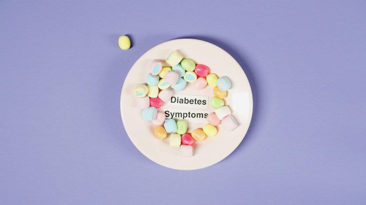 Colorful candies on a plate highlight diabetes symptoms against a purple background.