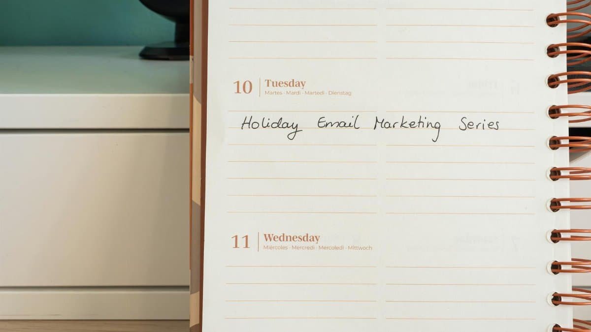 Planner open on a desk with handwritten 'Holiday Email Marketing Series' note.