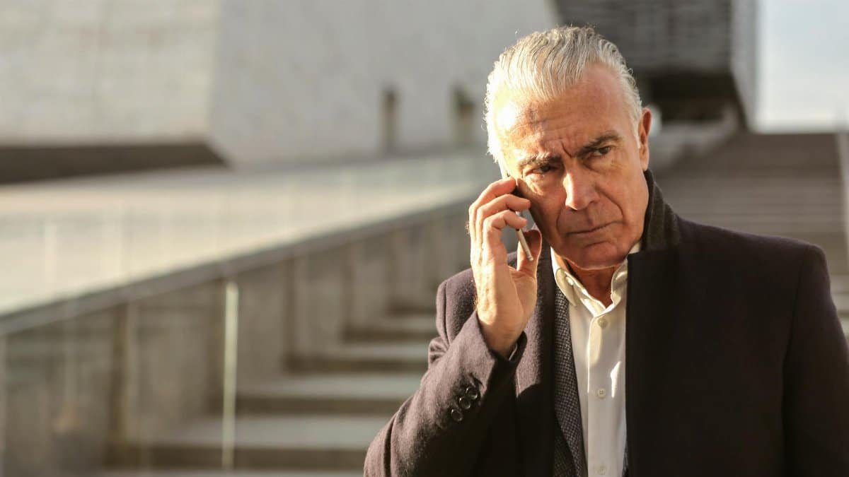 Serious senior businessman using a smartphone outdoors, conveying a professional and pensive mood.