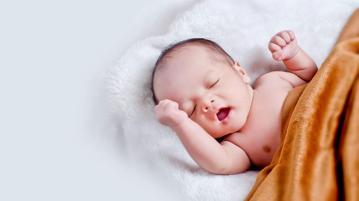 A peaceful sleeping infant wrapped in a soft, warm blanket on a cozy white surface.