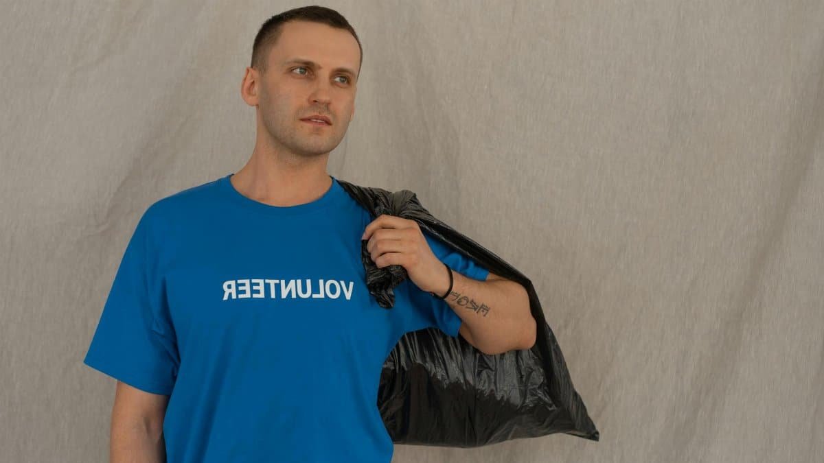 Male volunteer carrying garbage bag, symbolizing environmental efforts.