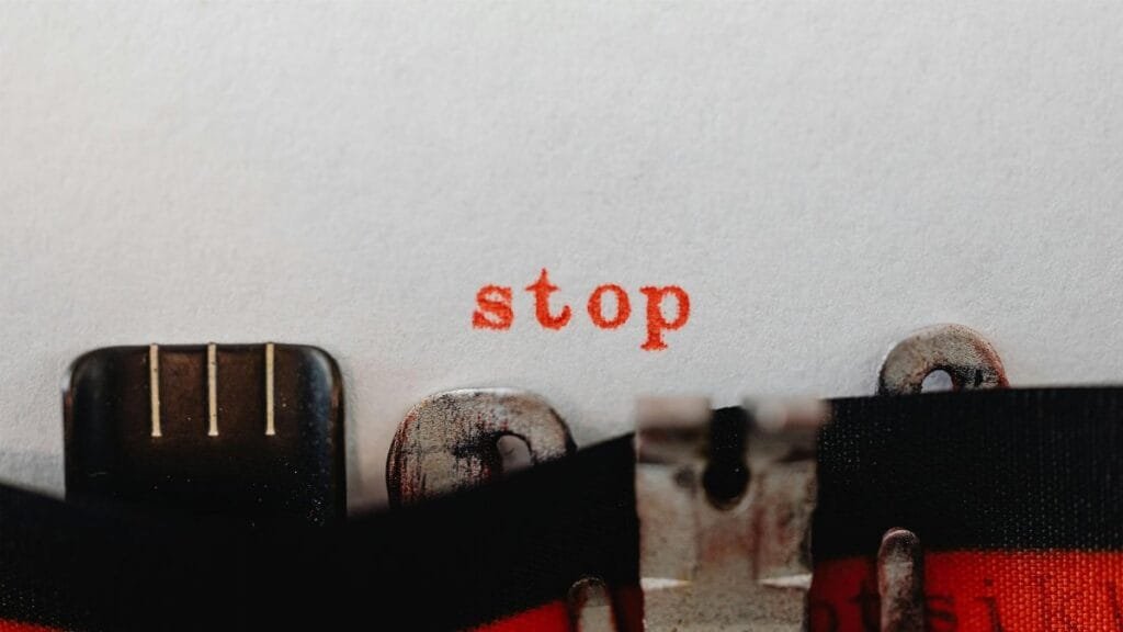 Close-up of a vintage typewriter typing the word 'stop' in red on white paper.