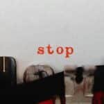 Close-up of a vintage typewriter typing the word 'stop' in red on white paper.