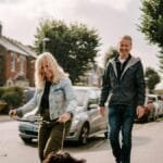 A joyous senior couple walking their dog on a sunny suburban street, enjoying the day.