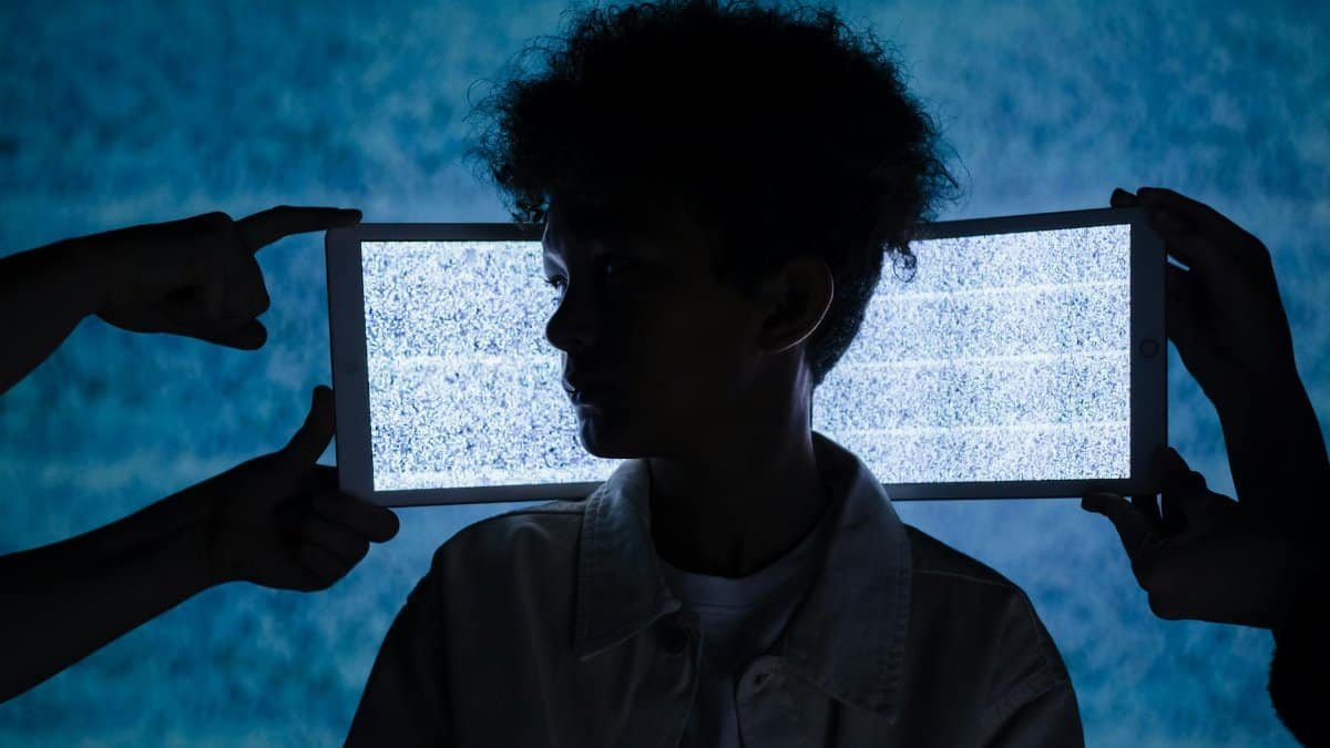 Artistic photo of a child's silhouette framed by digital tablets showing static, exploring technology and isolation.
