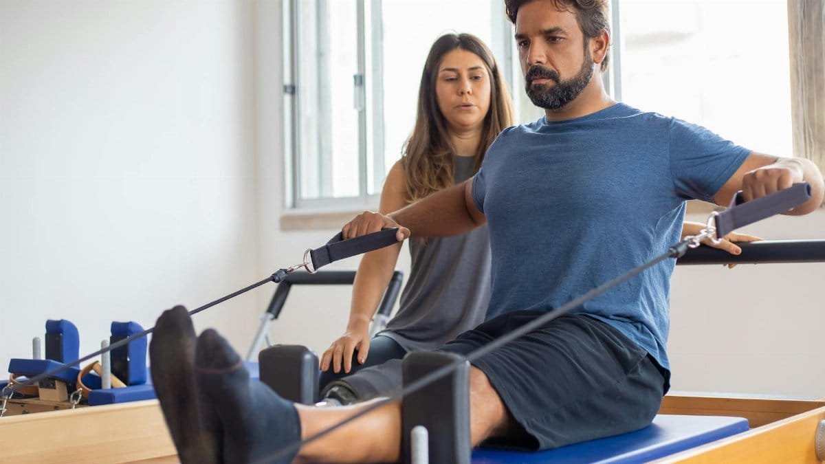Man with prosthetic leg working out with trainer in gym, showcasing strength and rehabilitation.