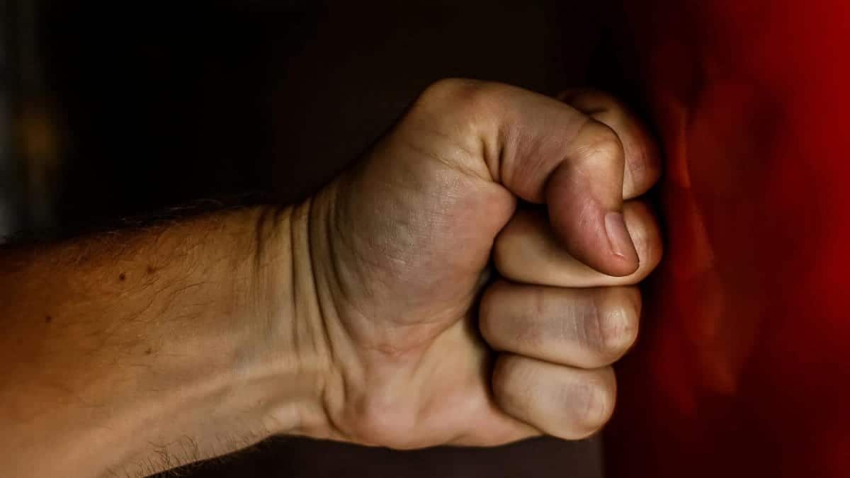 A detailed close-up of a clenched fist striking a red surface showcasing strength.