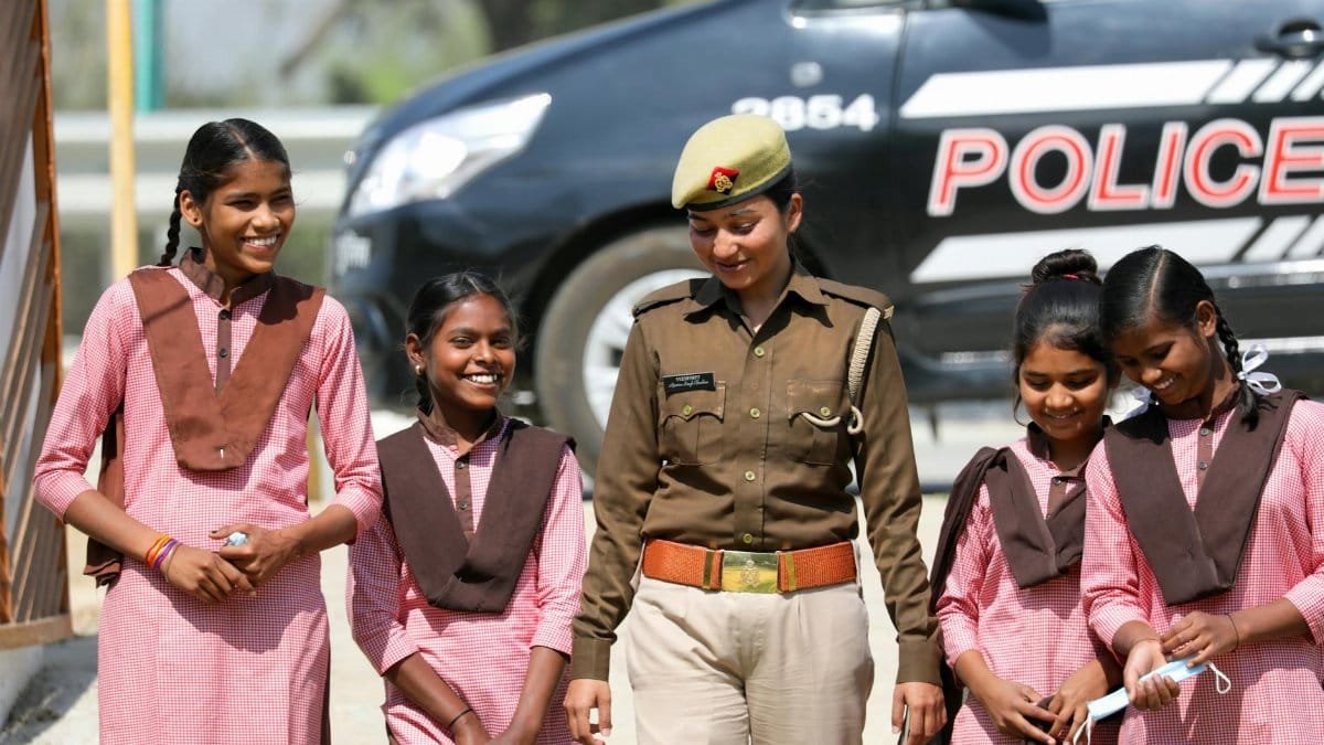A police officer shares a moment with smiling girls in uniform outdoors.