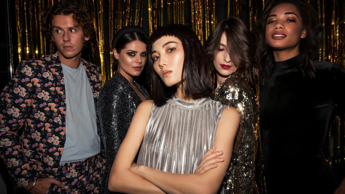 Chic group of young adults posing in glamorous attire, ready for a fashionable night out.