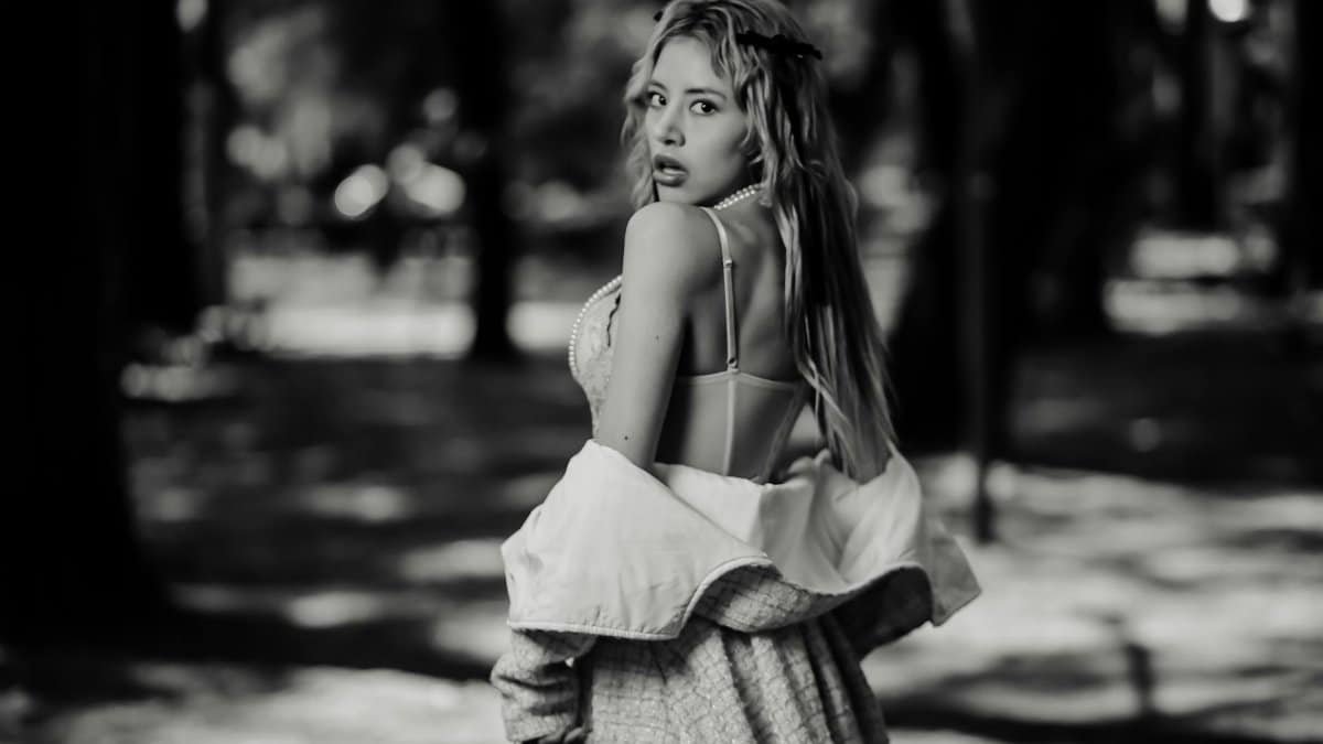 Black and white portrait of a woman outdoors in a park setting, exuding elegance and style.