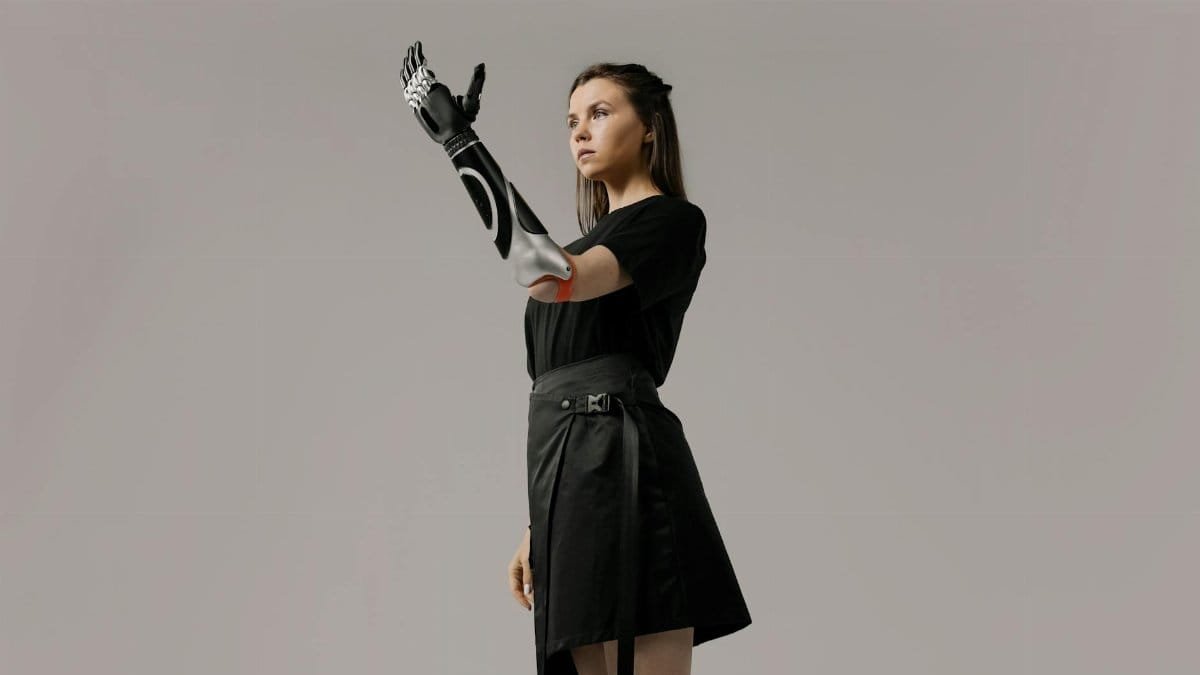 Empowering portrait of a young woman showcasing a futuristic prosthetic arm in a studio setting.