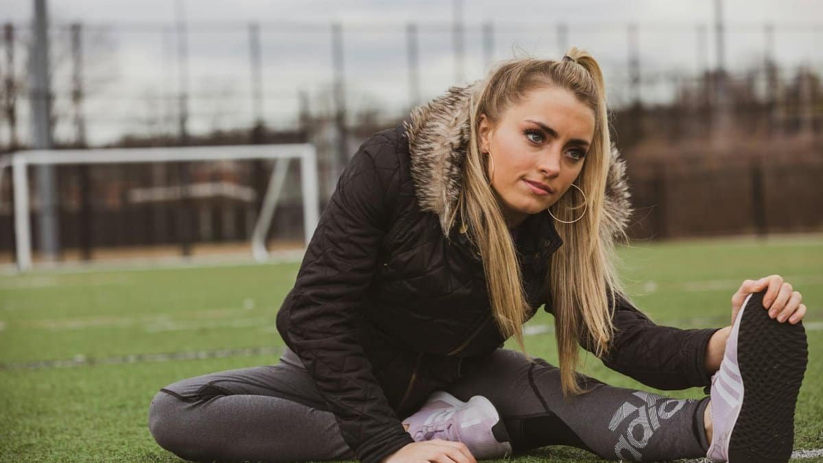 A young woman stretching on a soccer field in Oyster Bay, New York, on a cloudy day.
