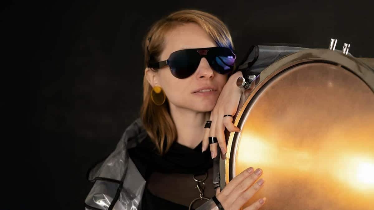Stylish woman posing with sunglasses and glowing light in a studio shoot.