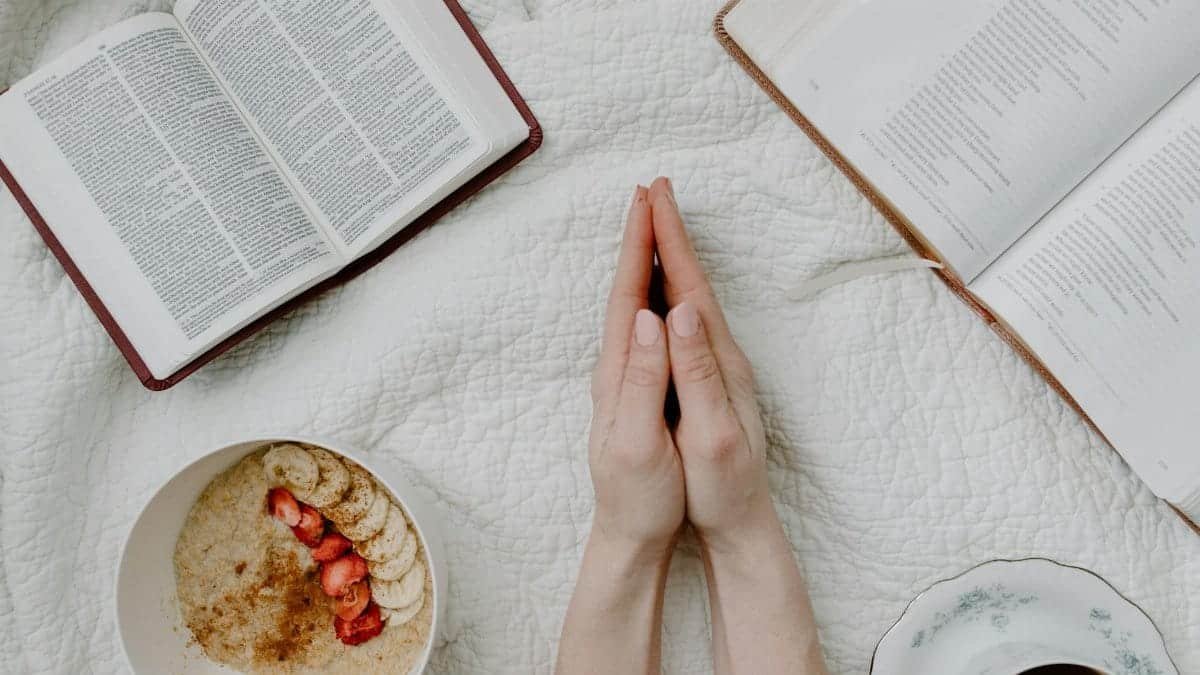 A serene morning scene with a person praying, an open Bible, oatmeal, and coffee.