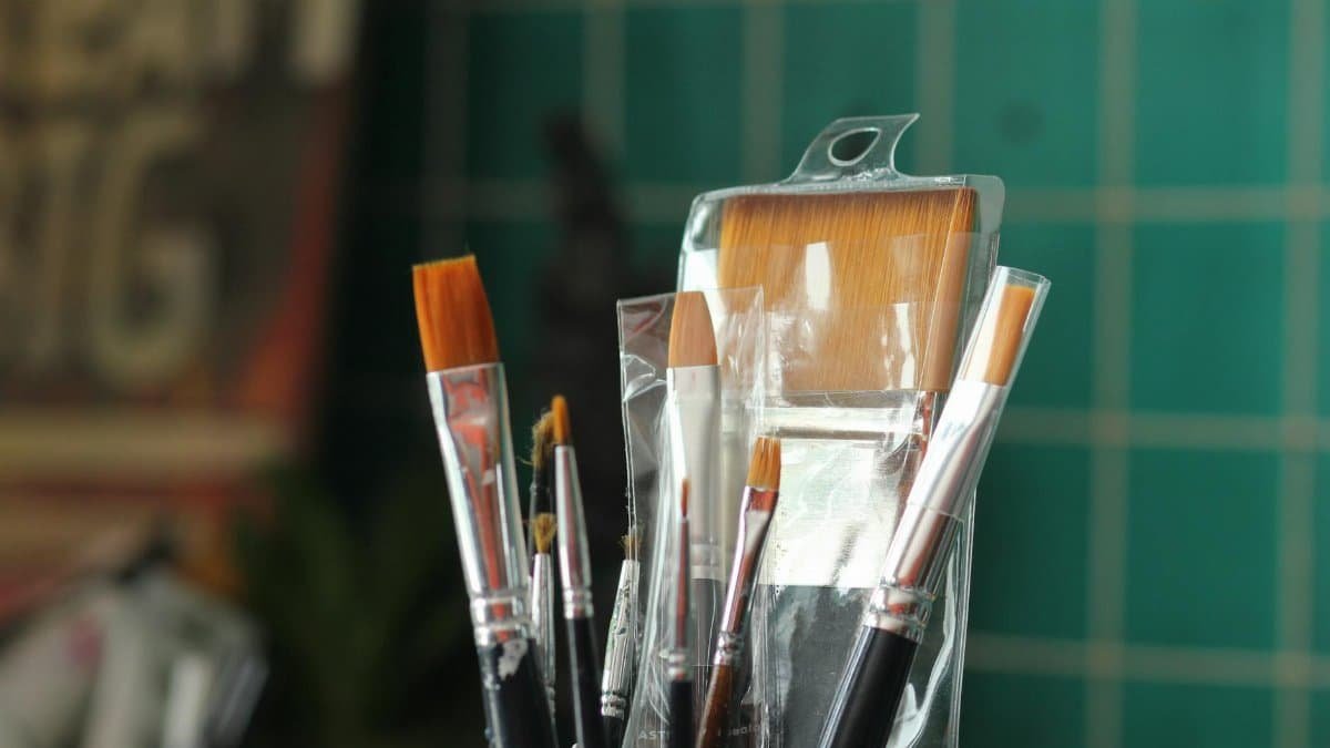 A collection of new paint brushes in a plastic container, ideal for art projects.
