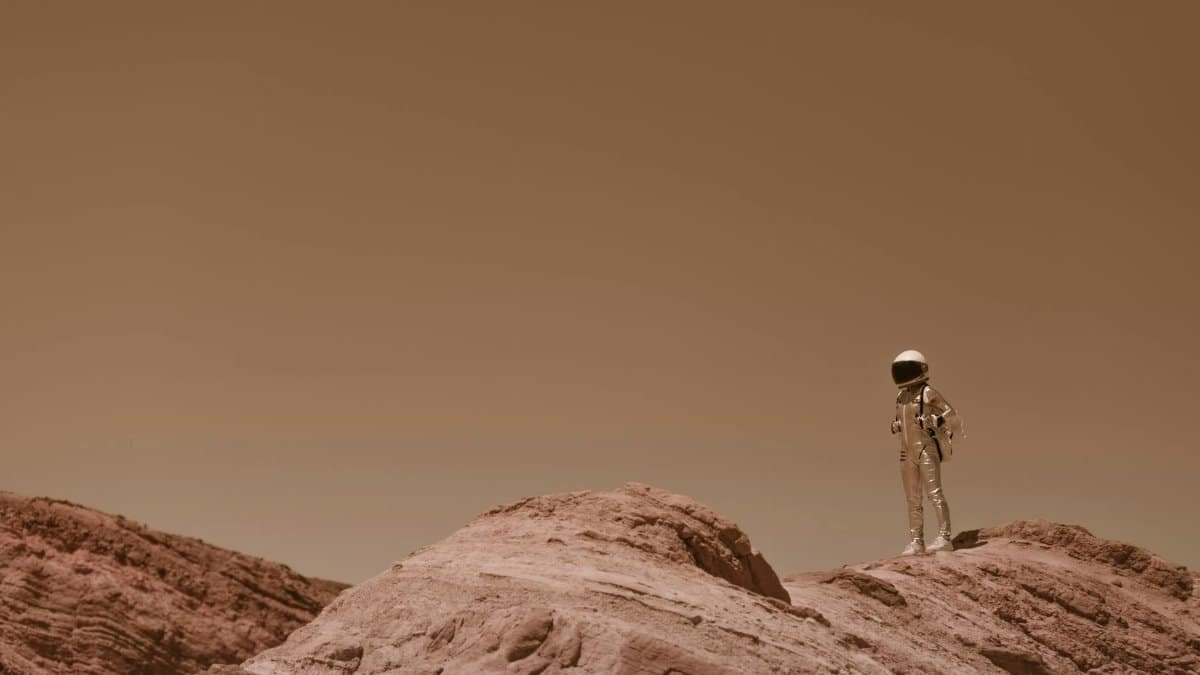Astronaut in full gear exploring rocky desert resembling Mars landscape.