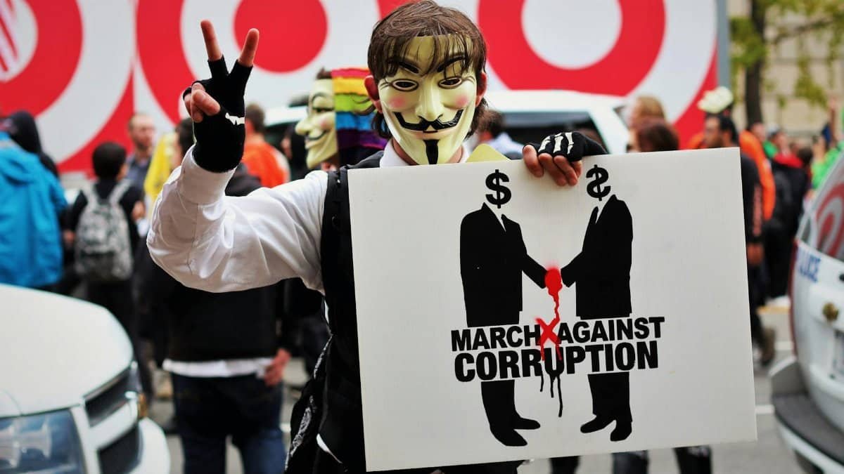 A protester wears a Guy Fawkes mask holding a sign at a rally against corruption in Washington, DC.