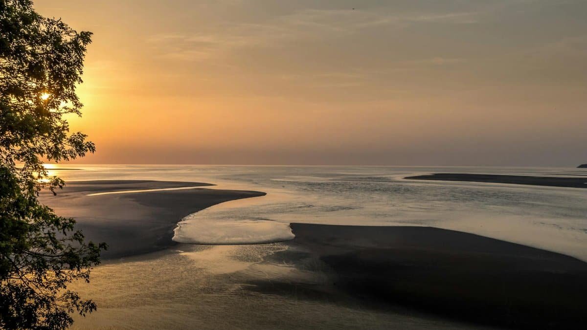 Beautiful sunset at Le Mont-Saint-Michel in Normandy, France showcasing low tide and serene ocean views.
