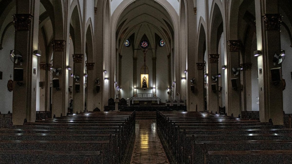 Grand church interior with arches, stained glass, and wooden pews reflecting a serene atmosphere.