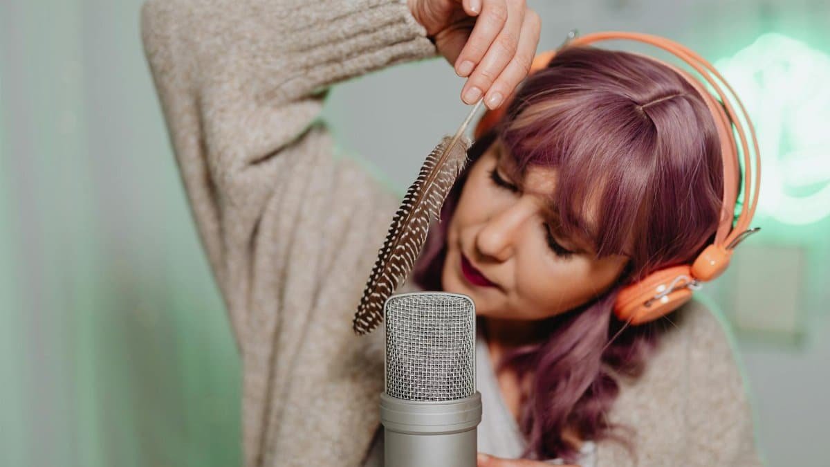 Caucasian woman using a feather for ASMR with a microphone indoors.