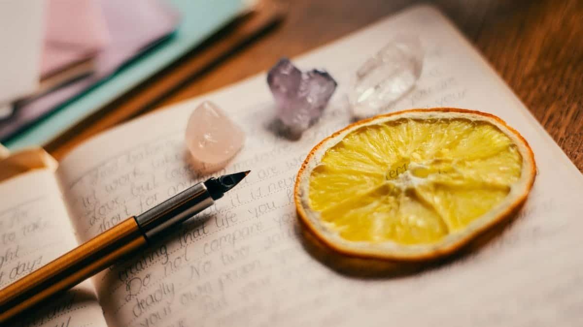 An artistic journal layout featuring a citrus slice, crystals, and a fountain pen for creative inspiration.