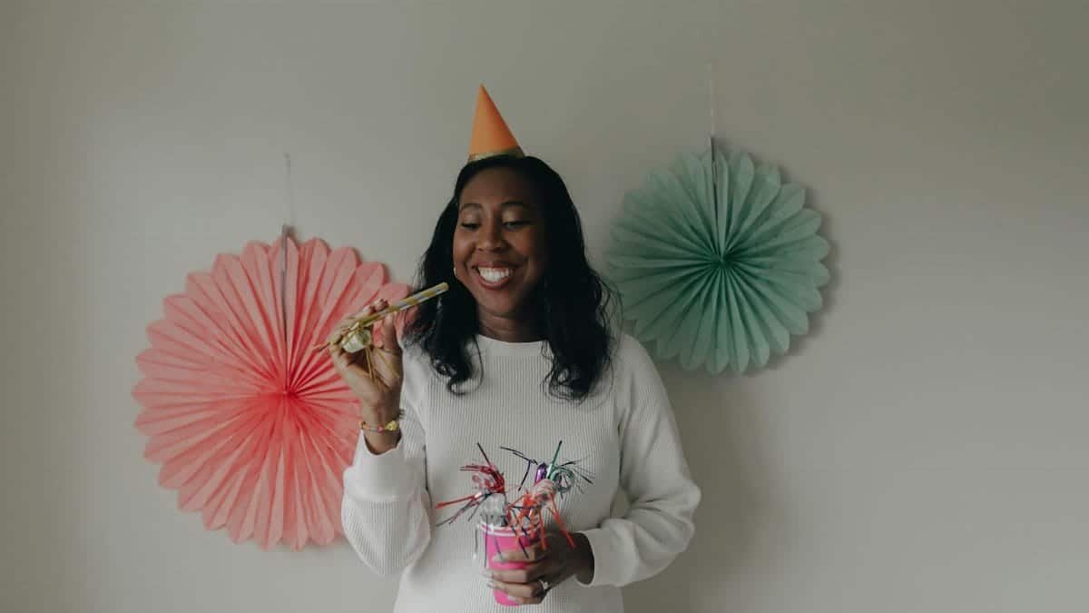 A happy woman celebrating her birthday with colorful decorations and party props.