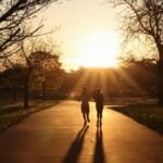 Silhouetted runners on a park path at sunrise in Stamford, CT, capturing the tranquility of early morning exercise.