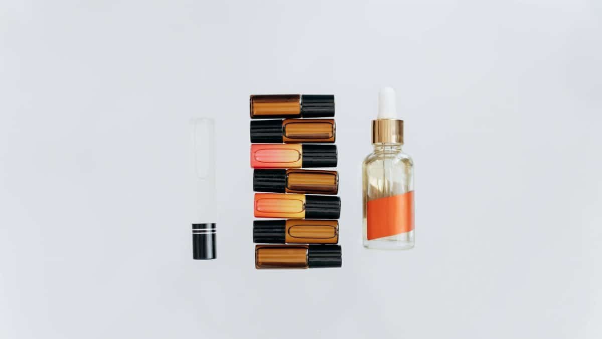 Stylish arrangement of essential oils and lipsticks on a white background, perfect for beauty and wellness themes.