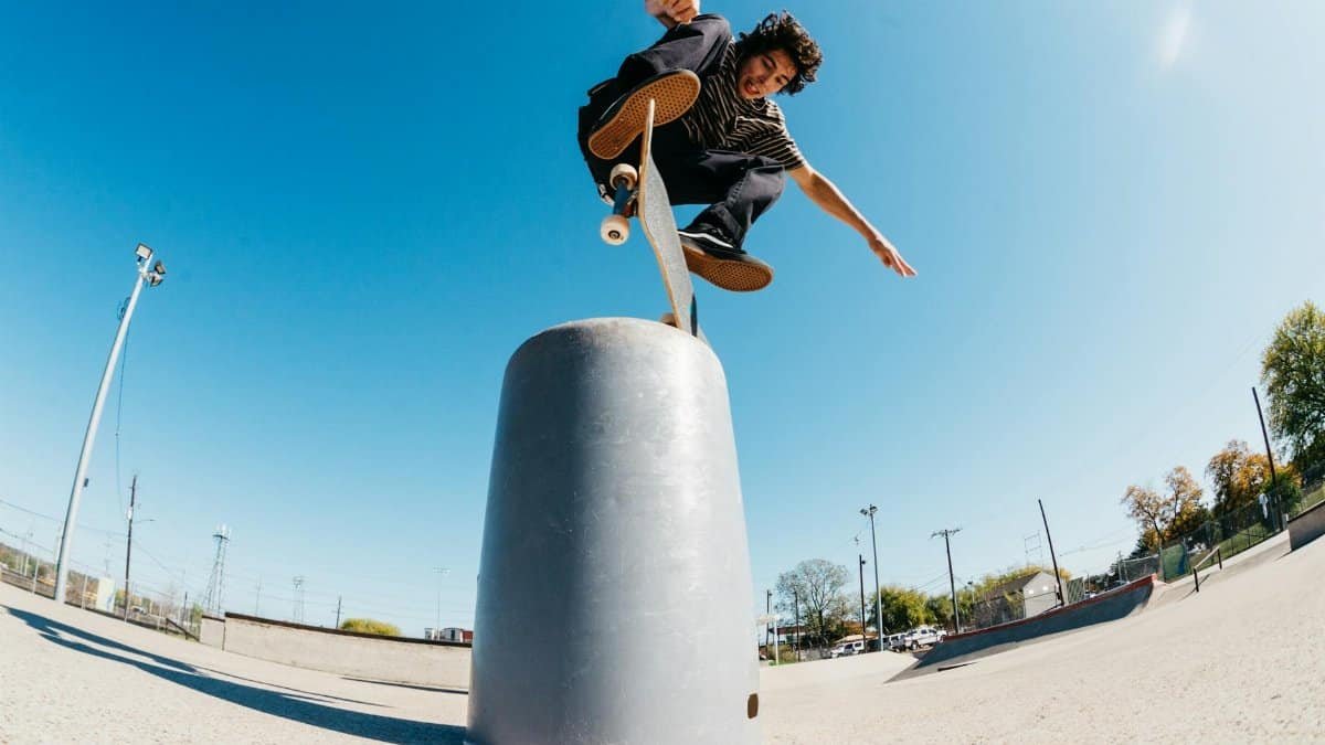 Skateboarder performing a trick in a sunny outdoor skate park.