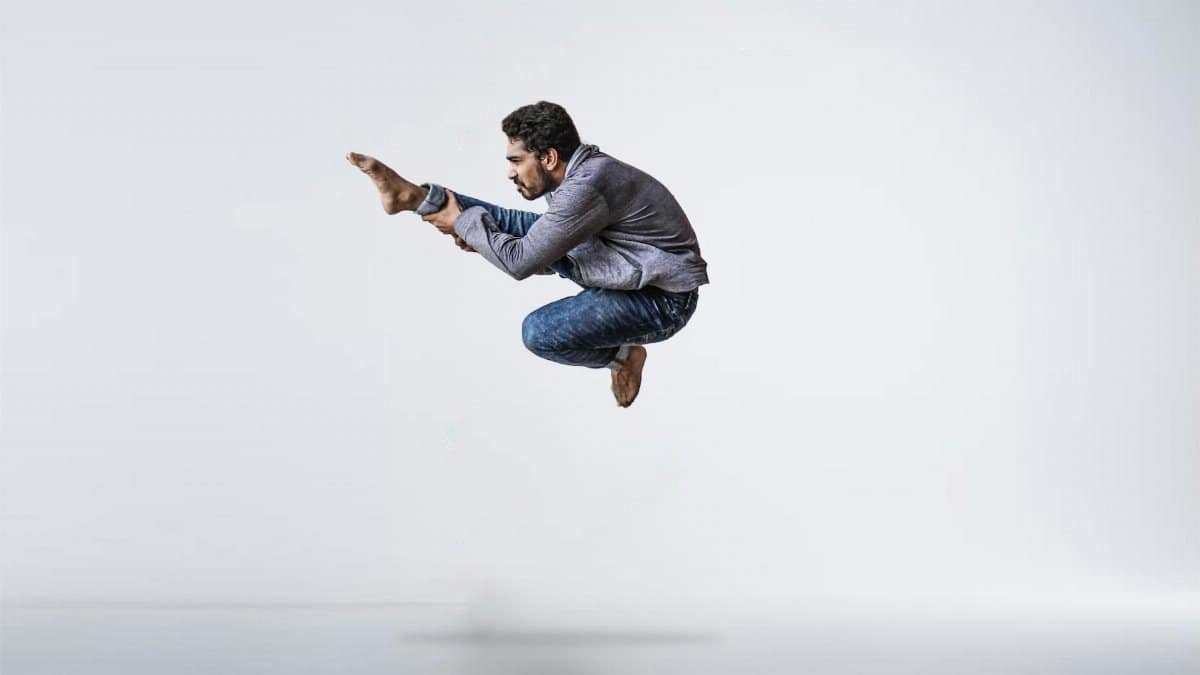 A male contemporary dancer gracefully leaps with precision and energy in a studio setting.