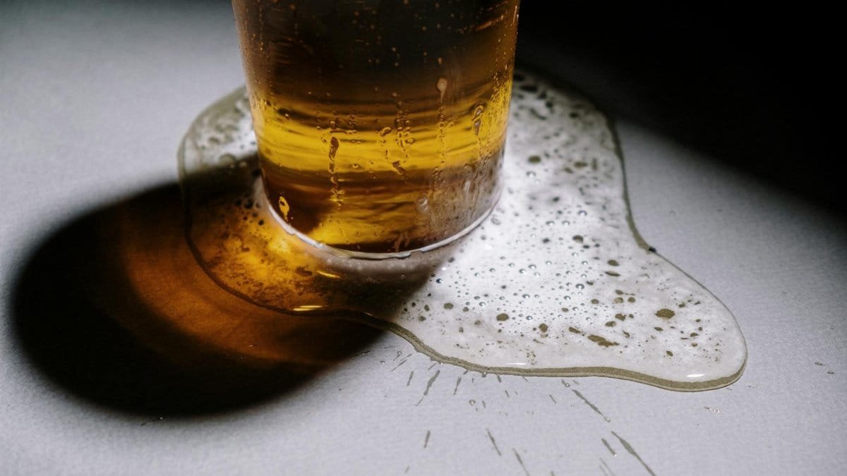 Close-up of an overflowing beer glass with foam and shadows, perfect for food photography.
