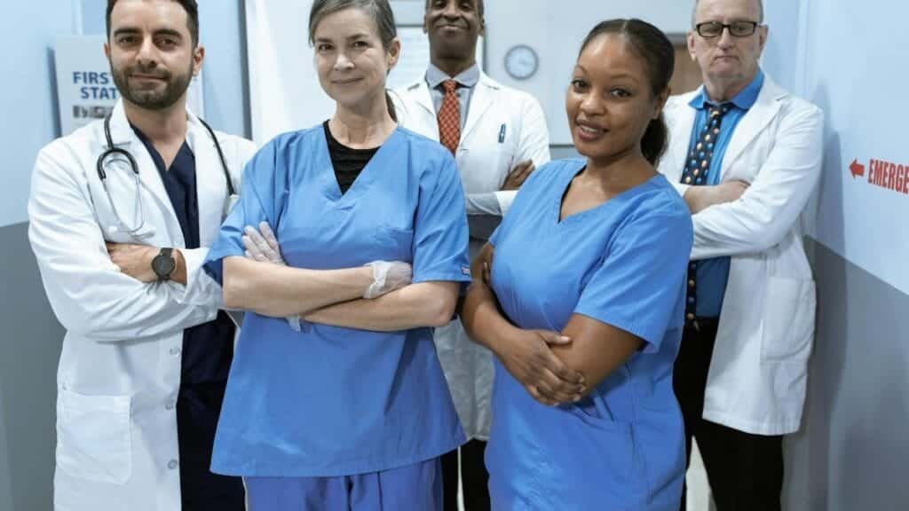 A diverse team of doctors and nurses smiling confidently in a hospital setting.