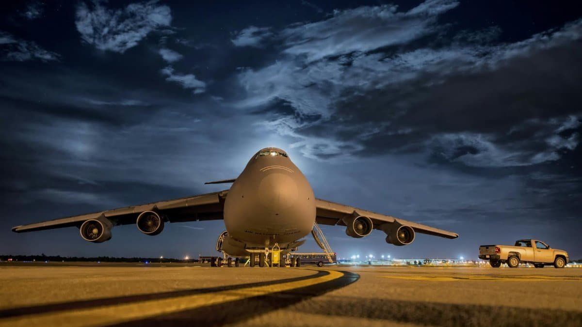 A large cargo plane stationed on the tarmac under the night sky, ready for transport.