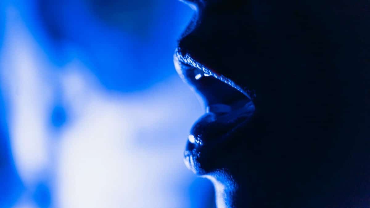 Close-up abstract image of an open mouth silhouette in dramatic blue lighting.