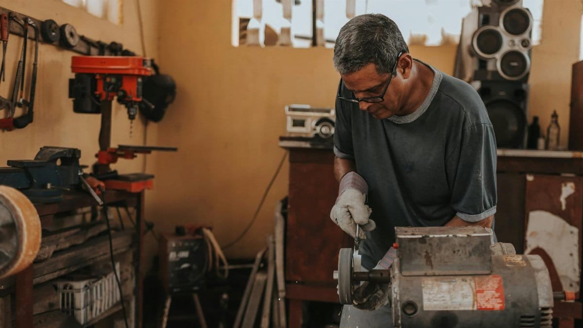 A skilled artisan focuses on metalwork with precision tools in a workshop.