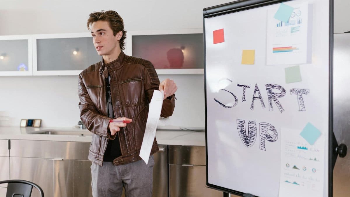 A young entrepreneur gives a presentation on startup strategies indoors with a flip chart.