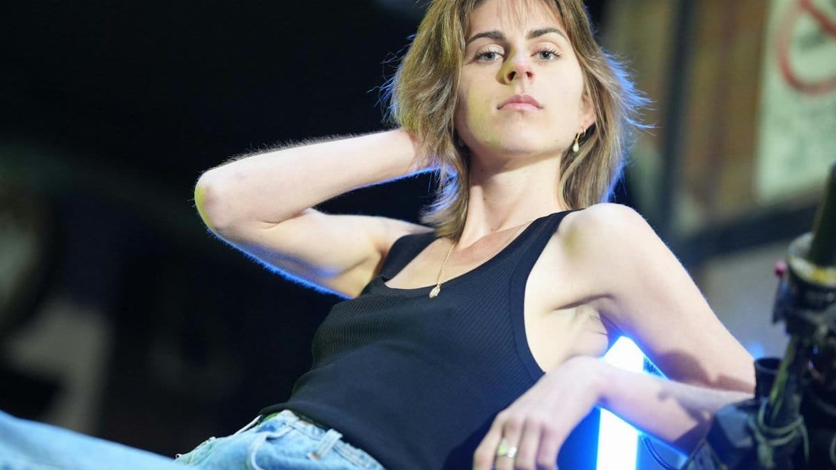 Fashion model confidently posing in a black tank top indoors, showcasing urban style.