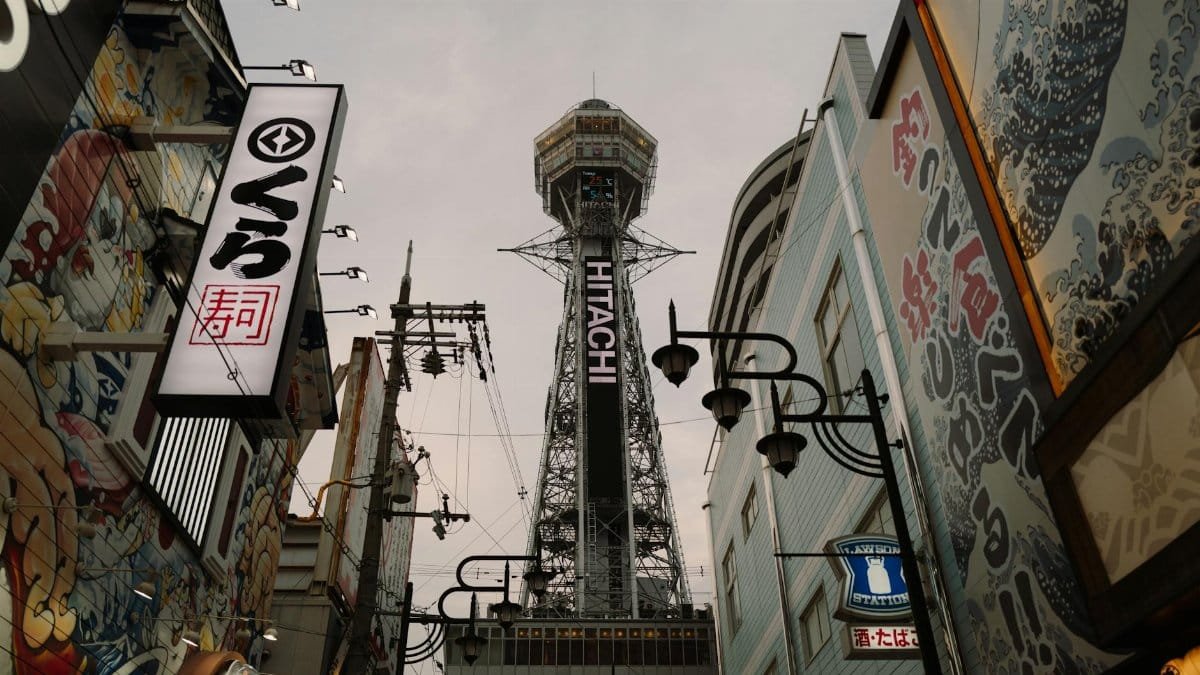 View of Osaka's Tsutenkaku Tower amidst colorful street art and urban architecture, a blend of tradition and modernity.