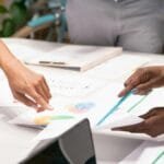 A diverse team collaborating on business strategies with charts and documents in an office setting.