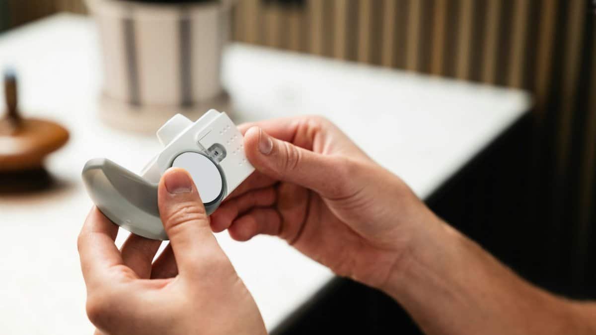 Close-up of hands holding an asthma inhaler, indoors in a modern setting.