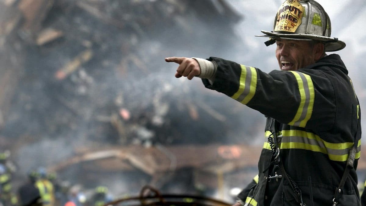 A firefighter in action at a disaster scene, directing rescue operations amidst smoke and debris.