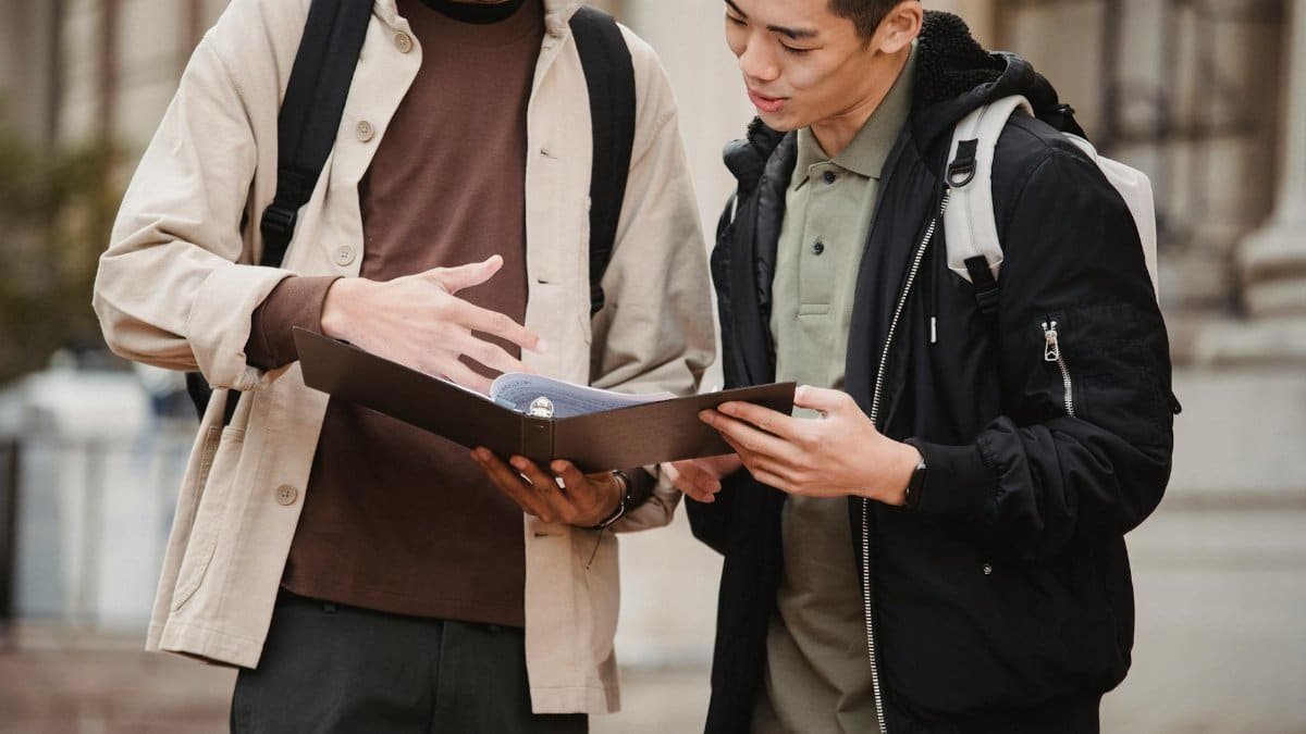 Two young men discussing a project outdoors on a university campus, showcasing collaboration and learning.