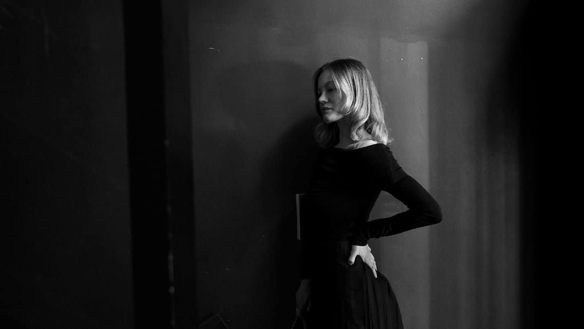 Black and white portrait of a woman in an elegant pose, exuding a classic and mysterious aura.