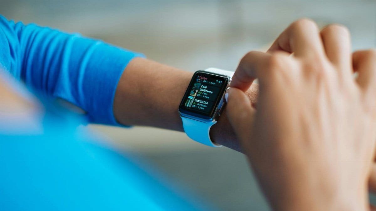 Person interacting with a smartwatch, showing a fitness application on the screen.