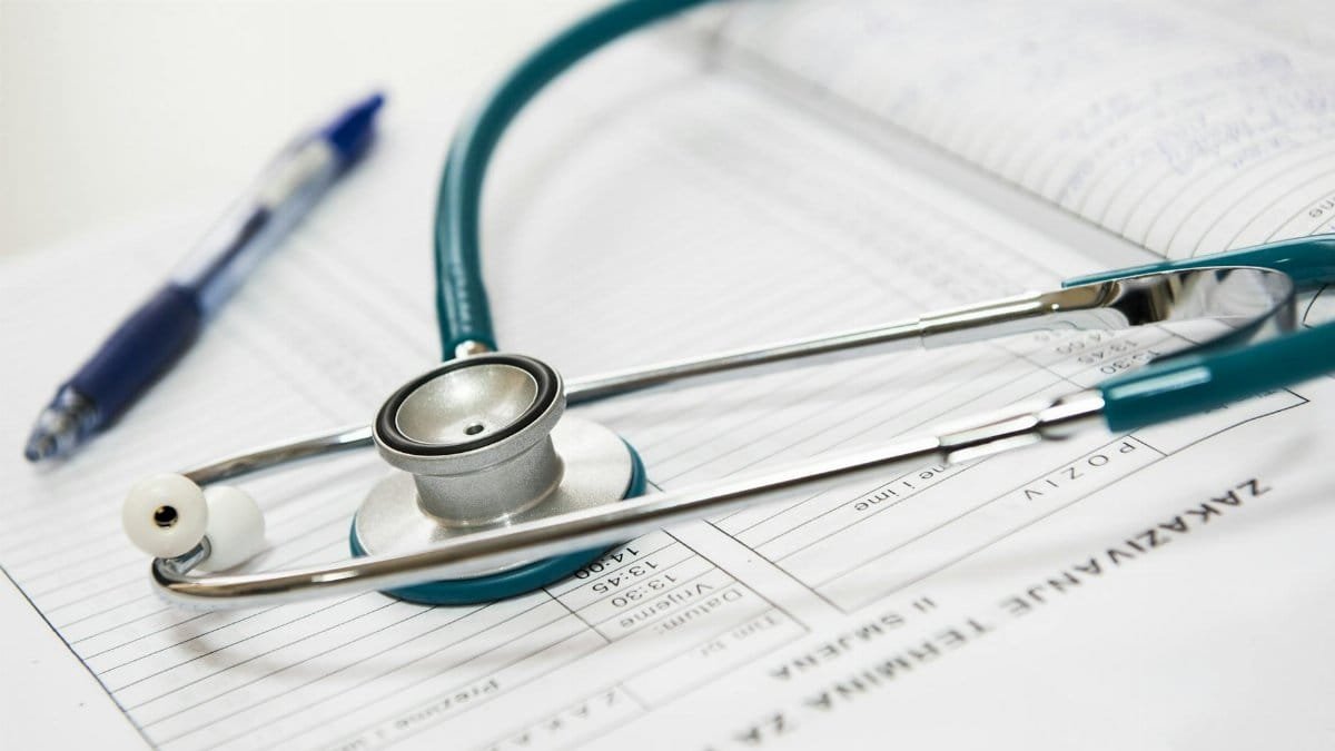A stethoscope and pen resting on a medical report in a healthcare setting.