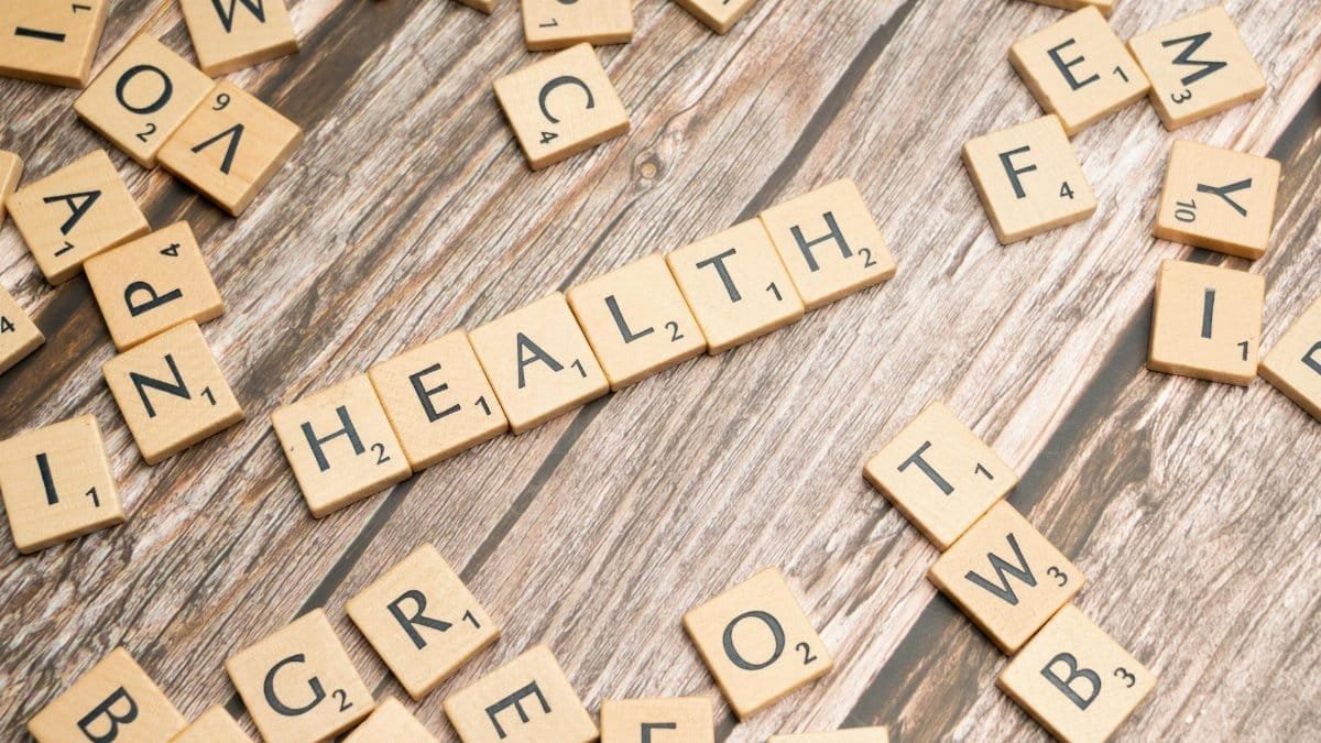 Scrabble tiles spelling 'HEALTH' on wooden surface, symbolizing wellness.