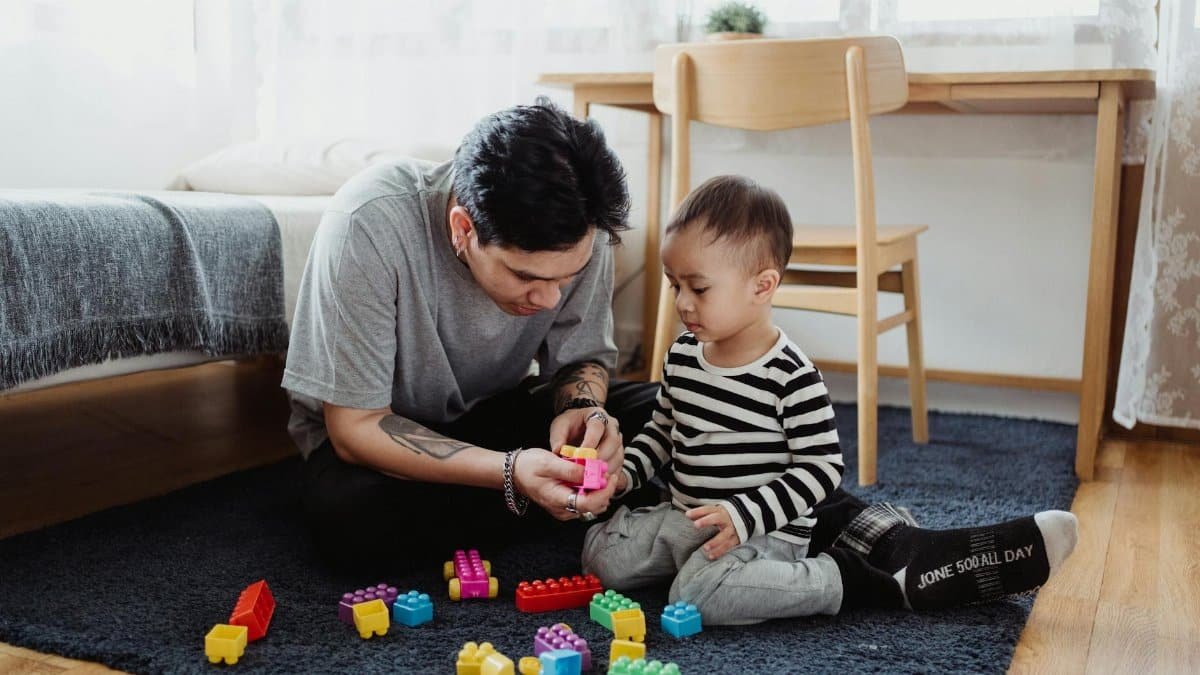 Father and son bonding over colorful building blocks in a cozy room.