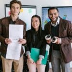 Diverse young entrepreneurs showcasing a new product prototype in a modern office.